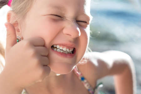 Portrait of a little girl with a wobbly baby tooth and a thumb up.の写真素材