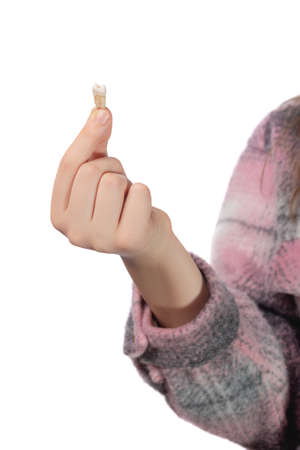 The child holds his molar tooth in his hand. Studio photo isolated on white background.の写真素材