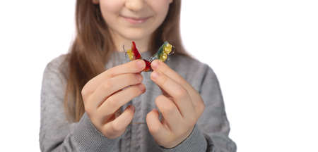 Cute little girl posing in the studio holding an orthodontic appliance in her hand. The concept of oral hygiene in childhood. Photo on a white background.の写真素材