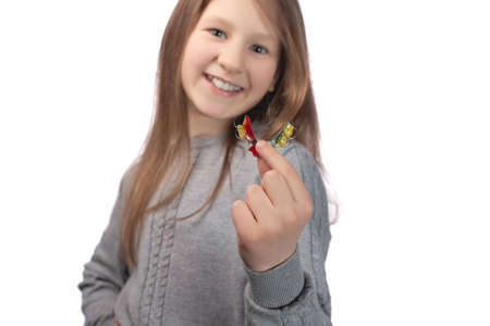 Cute little girl posing in the studio holding an orthodontic appliance in her hand. The concept of oral hygiene in childhood. Photo on a white background.の写真素材