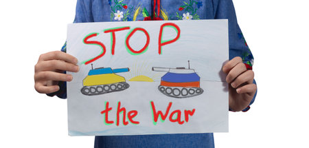 A little sad Ukrainian girl holds a drawing in her hands with the inscription Stop the war. Studio photo on a white background.
