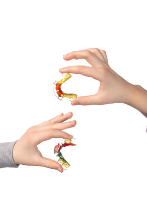 Two children's hands with orthodontic appliances on a white background. The concept of oral hygiene in childhood. studio photo.の写真素材