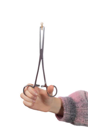 The child holds a child's molar tooth in a clamp. Studio photo isolated on white background.の写真素材