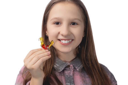 Cute little girl posing in the studio holding an orthodontic appliance in her hand. The concept of...