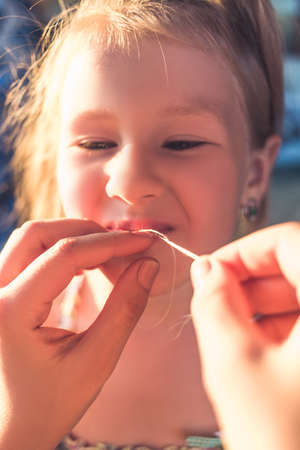 The process of removing a baby tooth using a thread.の写真素材