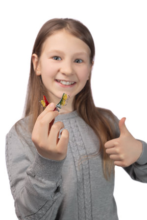 Cute little girl with orthodontic appliance showing thumbs up. The concept of oral hygiene in childhood. Studio photo on a white background.の写真素材