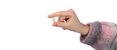 The child holds his molar tooth in his hand. Studio photo isolated on white background.の写真素材