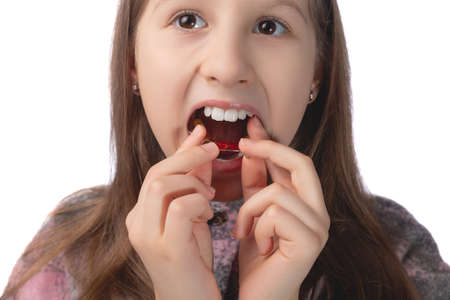 A cute little girl is putting on an orthodontic appliance. The concept of oral hygiene in childhood. Studio photo on a white background.の写真素材