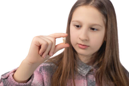 A cute little girl is holding a recently removed molar in her hand. Studio photo on a white background.の写真素材