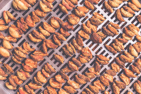 The process of home cooking dried fruits in an electric dryer. The stage of dehydration of fruits for storage and consumption in the winter. Lots of dehydrated apricots.の写真素材