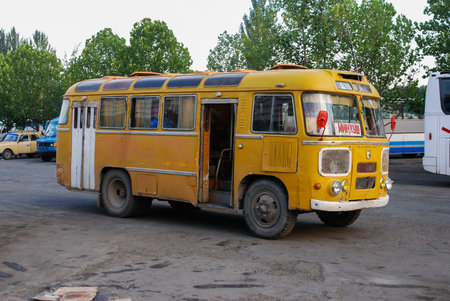 Old yellow bus on street of Bishkek, Kyrgyzstan. The plate in the fornt of bus shows the name of the...