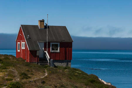 Red house of the fishing town in Greenland. Fjord in the background.のeditorial素材