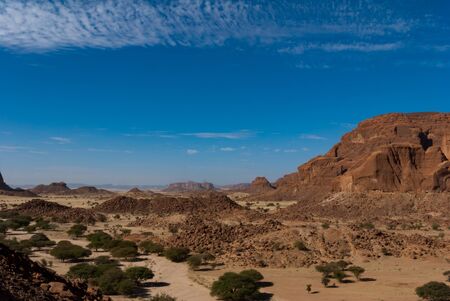 Natural rock formations, trees and small hut of nomad, Ennedi Plateau in Sahara desert, Chad, Africaの写真素材