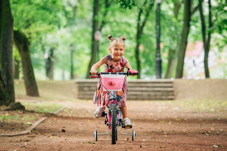 Smiling little girl on a bicycle in park. Cheerful child ridingの写真素材