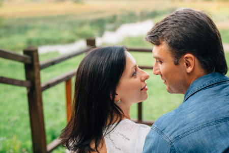 Young pretty happy couple sitting on wooden stairs in the park. Man and woman dating and flirting outdoors.の写真素材