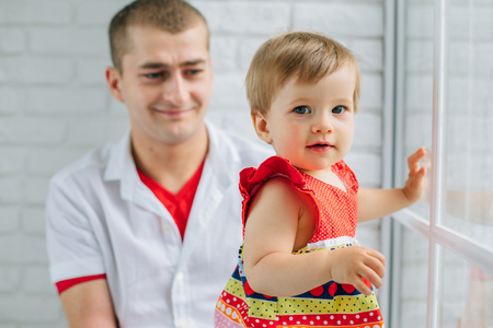 Father and little daughter sitting on windowsill. Man with cute little girl.の写真素材