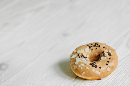 Glazed caramel donut on light wooden background placed in corner.の写真素材