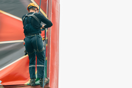 Industrial climber hangs a poster on a billboardの写真素材
