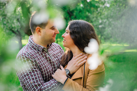 Young stylish happy couple in love hugging in blooming garden. Man and woman having romantic date outdoors.の写真素材