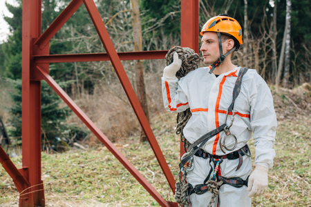 Industrial climber in uniform and helmet with rope in hand is ready for work. Professional worker.の写真素材
