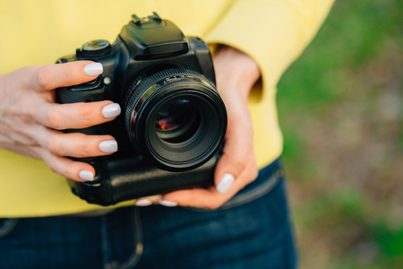 Girl with professional camera in hands. Close up of female photographer.の写真素材