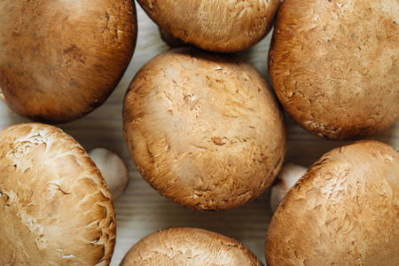 Brown champignon mushrooms lying on a wooden tableの写真素材