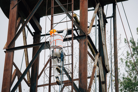 ndustrial climber in uniform and helmet climbing the stairs. Professional worker doing his risky job on water tower.の写真素材