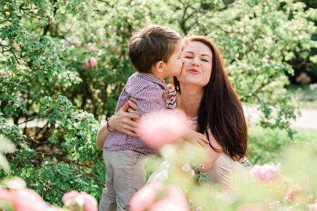Happy mother with cute little boy having fun outdoors. Cheerful woman playing with her son in park. Joyful motherhood.の写真素材