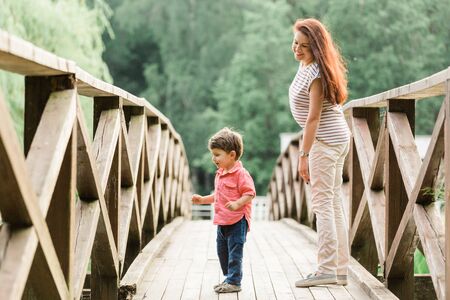 Mother having fun with cute son in summer park. Happy woman with cheerful little boy outdoorsの写真素材