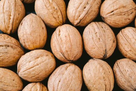 Walnuts with shells on dark background. Background of fresh whole walnuts.の写真素材