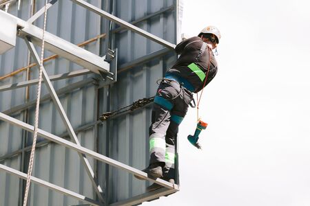 Industrial climber in helmet and overall working on height. Risky job. Professional workerの写真素材