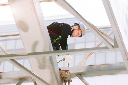 Industrial climber in helmet and overall working on height. Risky job. Professional workerの写真素材