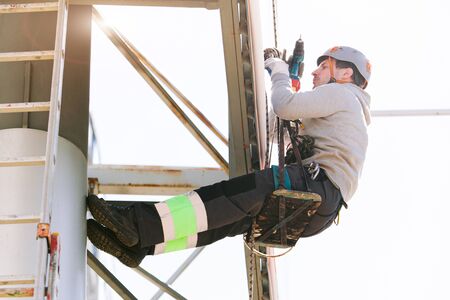 Industrial climber in helmet and overall working on height. Risky job. Professional workerの写真素材