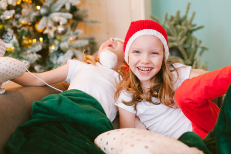 Two Happy cheerful Little girls in santa hat. Christmas time. Sisters having funの写真素材