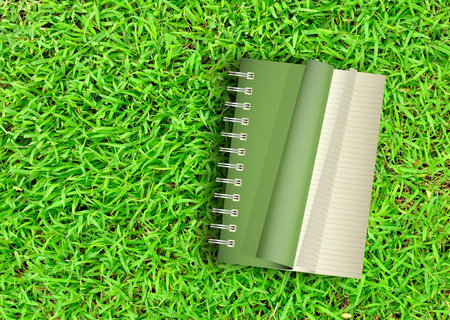 Green Notebook opening on green grass backgroundの写真素材