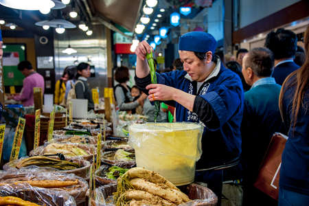 Nishiki Market, Kyoto, â October 22, 2016: A crowded marketplace. Young vendor is adding more pickled vegetable to the stand. There are assortments of pickle varieties in his store.のeditorial素材