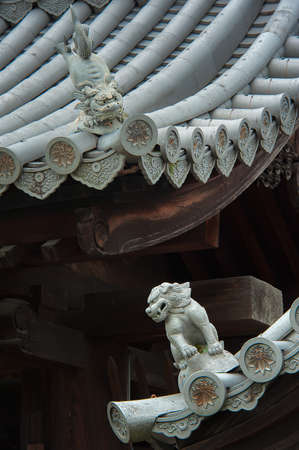 Mystical lion sculptures on the roof: The mystical roof guardians set to watch over men and women behaviour and faithfulness. Commonly used as part of ancient Japanese and Chinese architectures.の写真素材