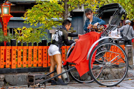 Rickshaw Taxi Ride. Gion Shirakawa Street, Kyoto, Japan â October 23, 2016: Rickshaw driver secures a red blanket to his customer as she is settling down for her journey.のeditorial素材