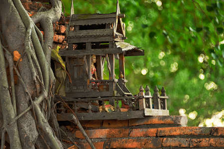 SPIRIT HOUSE AND TREE ROOTS INTERTWINED. Miniature house for guardian spirit. A dedicated structure to honour the guardians of the land that is found in the Southeast Asian countries of Burma, Cambodia, Laos, and Thailand.の写真素材