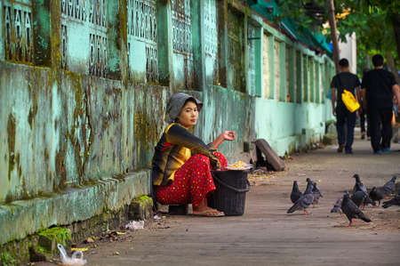 Yangon, Myanmar - 21 October, 2017: Burmese street vendor selling pigeon food on a pavement in Yangon Chinatown neighborhood.のeditorial素材