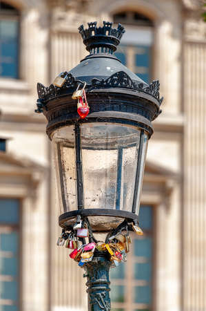 Bundle of padlocks and a red heart keyring locked onto a lamppost at âPont des Artsâ pedestrian bridge in Paris.の写真素材