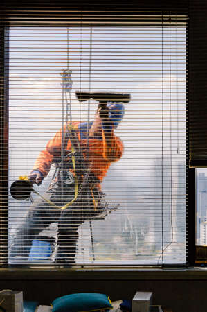 Bangkok, Thailand - December 1, 2015: High-rise window cleaning - a daring profession. A window cleaner fearlessly hanging on his ropes, cleaning the windows of a high-rise building.のeditorial素材