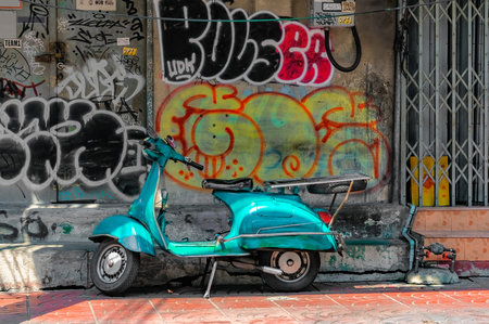 Chinatown, Bangkok â March 20,2021: Old scooter left unattended on the pavement in front of an old wall with graffiti all over it.のeditorial素材