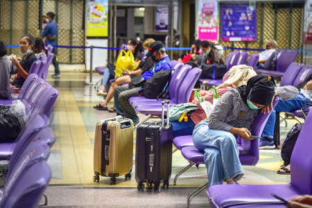 Bangkok, Thailand - March 20, 2021: Commuters at waiting hall at Bangkok Train Station - Hau Lumphong. Everyone wears a facemask and keeps their social distance.のeditorial素材