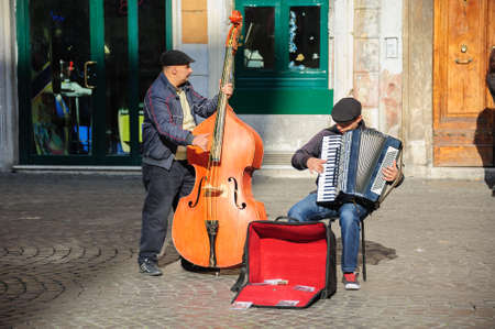 Rome, Italy - January 01, 2013: two musicians play double bass and an accordion near Santa Cecilia in Trastevere Church for tips and also to promote their song on CD.のeditorial素材