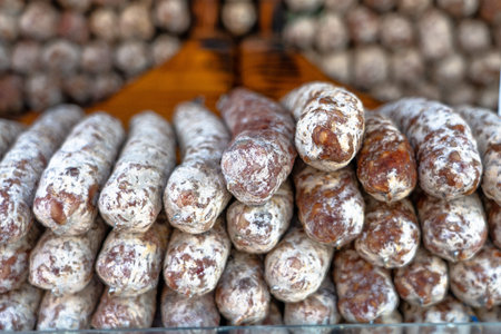 Stacks of dry-cured sausages - saucisson, typically made of pork, or a mixture of pork and other meats. Some variation contains spices and herbs, mushrooms, dried fruits, and nuts.の写真素材