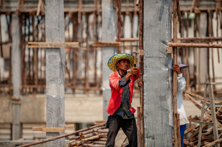 Bangkok, Thailand September 5, 2015: Construction worker nails temporary wooden poles as struts to concrete columnsのeditorial素材