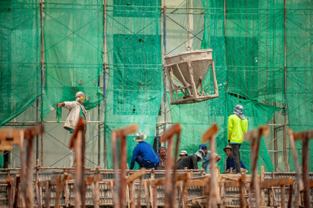 Bangkok, Thailand September 5, 2015: Concrete bucket hoisted down by crane delivering to a team of construction workers below, for pouring concrete to formwork.のeditorial素材