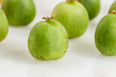 A mini kiwiberry in selective focus against rows of neatly lined kiwiberries. Also known as baby...