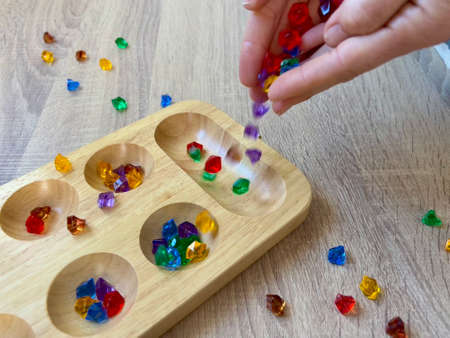 woman's hands dropping colored beads into a boxの写真素材